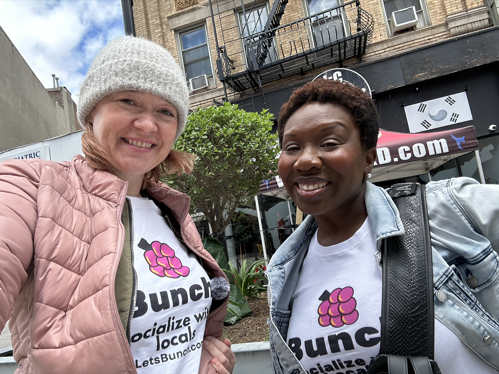 Two Bunch members smiling in Bunch tees on a Jersey City street