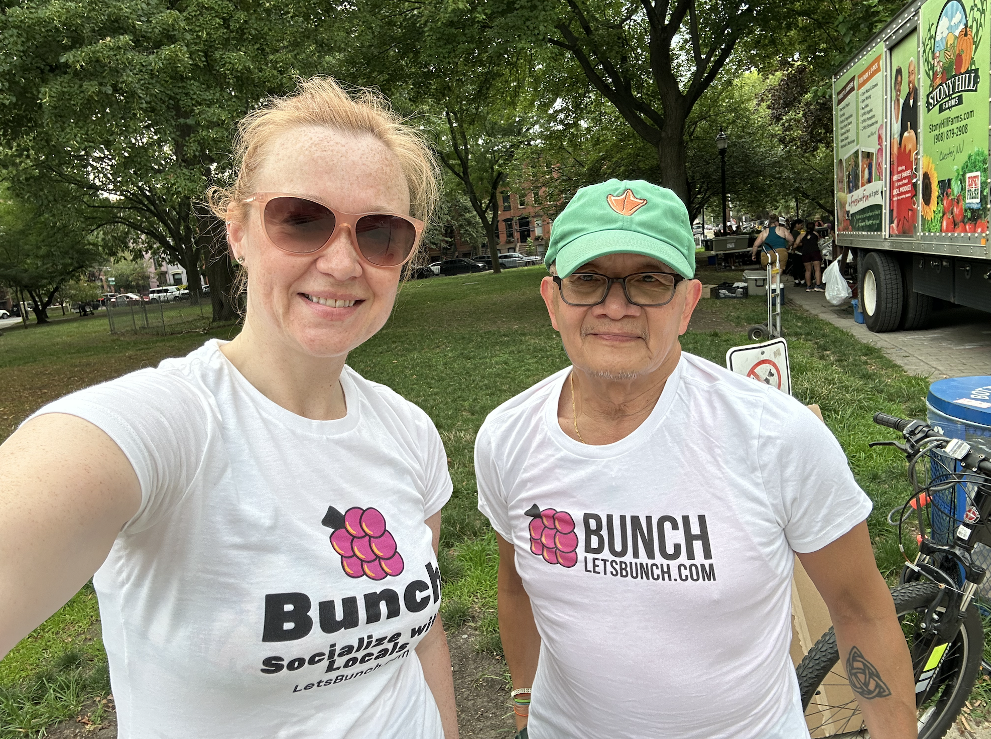 Two Bunch members in Bunch tees at a farmers market in the park